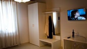 Une pièce comprenant une armoire, un banc, un téléviseur et une table en verre.