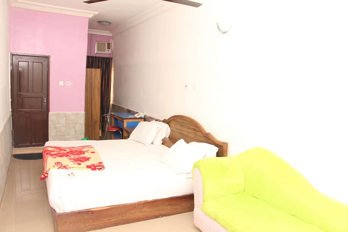 Un dormitorio con cama, una silla, un escritorio y una puerta.