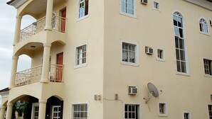 Een meerlaags gebouw met een balkon op de tweede verdieping, meerdere ramen en een schotelantenne.