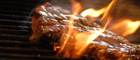 Un filete asándose en una parrilla con llamas visibles.