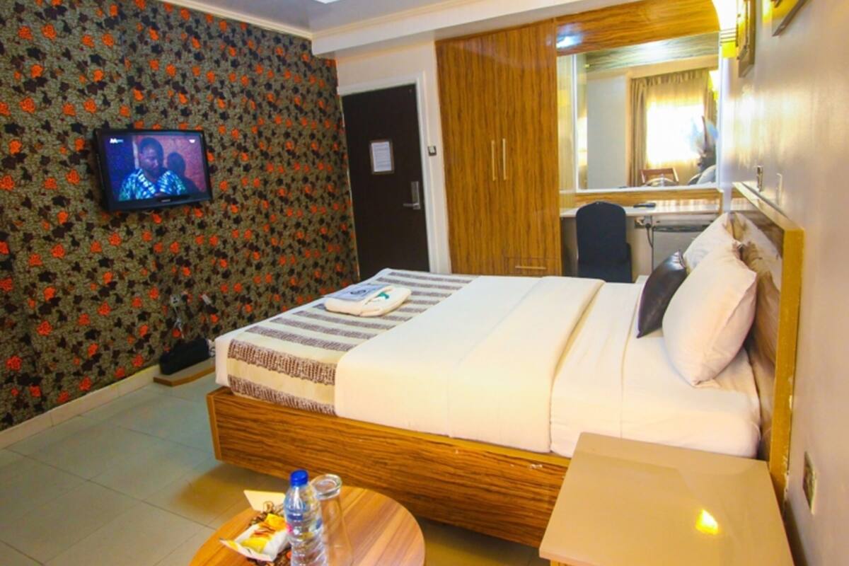 A hotel room with a bed, a television, a desk, and a mirror.