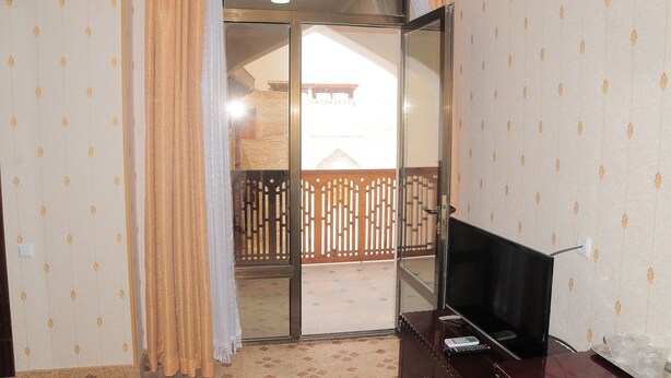 Een kamer met een schuifglasdeur die uitkomt op een balkon met een houten hek.