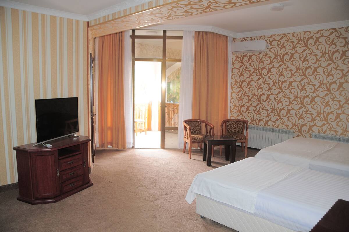 A hotel room with a bed, a TV on a wooden cabinet, a chair, and a table.
