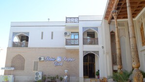 A building with a sign reading "Kafir Kosher Food" and a bear statue outside. - Kabir Hotel (Bukhara)