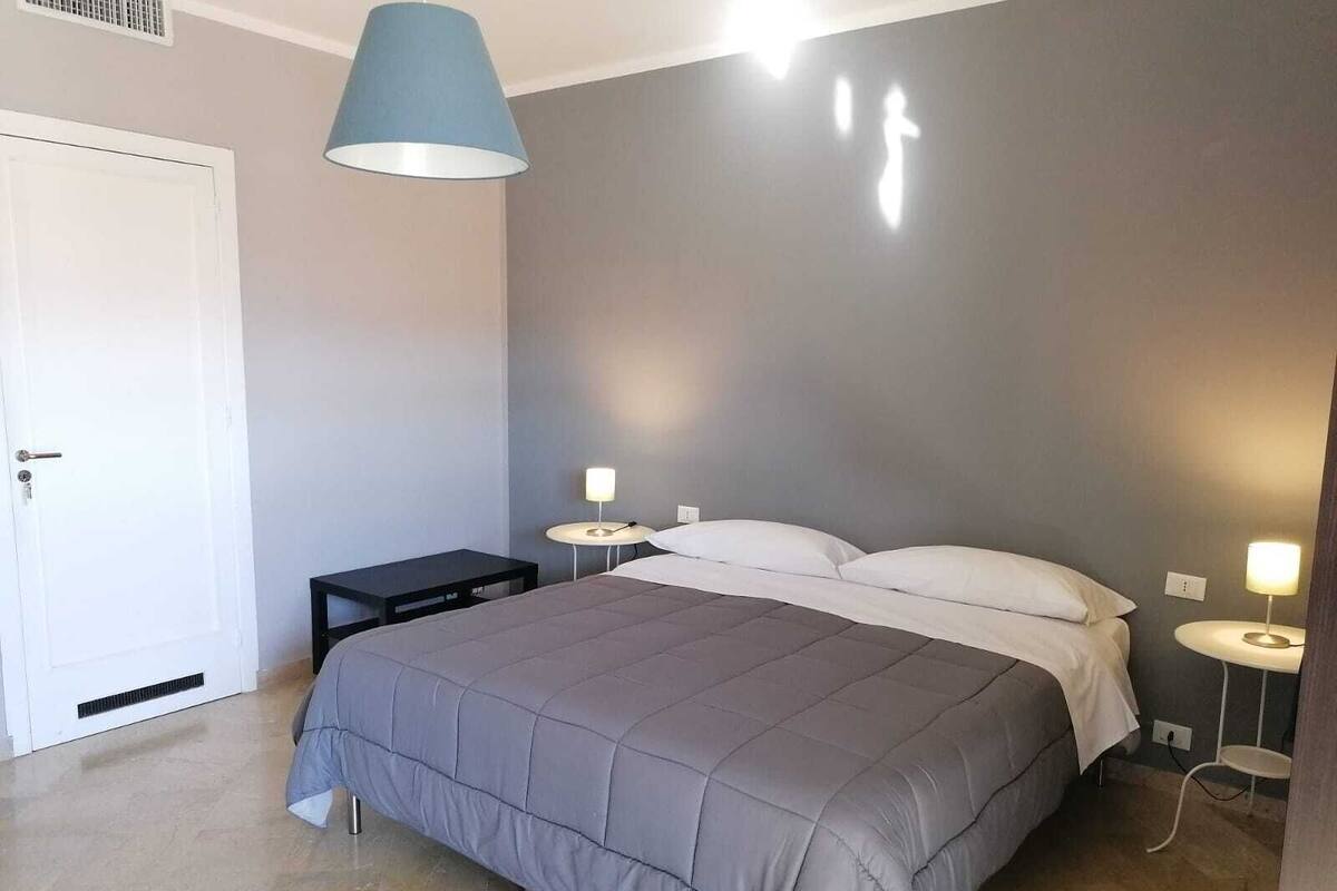 Una camera da letto con un letto, due comodini, una lampada e una porta.