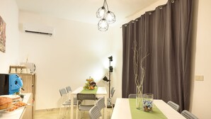 Un comedor con una mesa preparada para cuatro personas, sillas, una cafetera y un frutero.