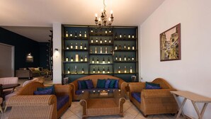 A living room with wicker furniture, a glass coffee table, and a wine display wall. - Fedra Mare Apartment (Corfu)