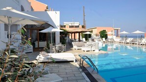 A poolside area with lounge chairs, umbrellas, and a clear blue pool. - Fedra Mare Apartment (Corfu)