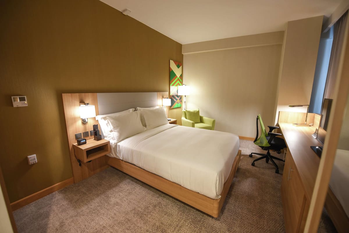 Une chambre d’hôtel avec un grand lit, des lampes de chevet, un bureau avec un ordinateur et une chaise.