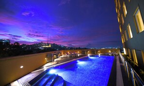Una piscina sul tetto con vista sulla città al crepuscolo.