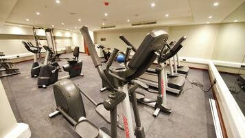 Un gimnasio con diversas máquinas de ejercicio, incluyendo cintas de correr y elípticas.