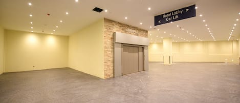 Un vestíbulo amplio y bien iluminado con un elevador de coches y un cartel que indica el acceso al vestíbulo del hotel.