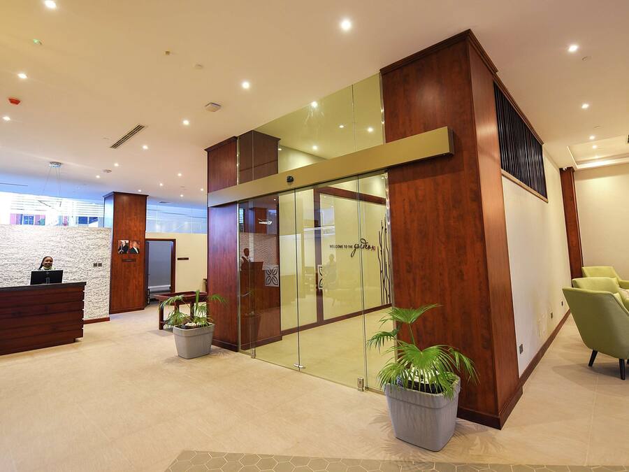 A modern reception area with a wooden reception desk, glass partitions, and green seating.
