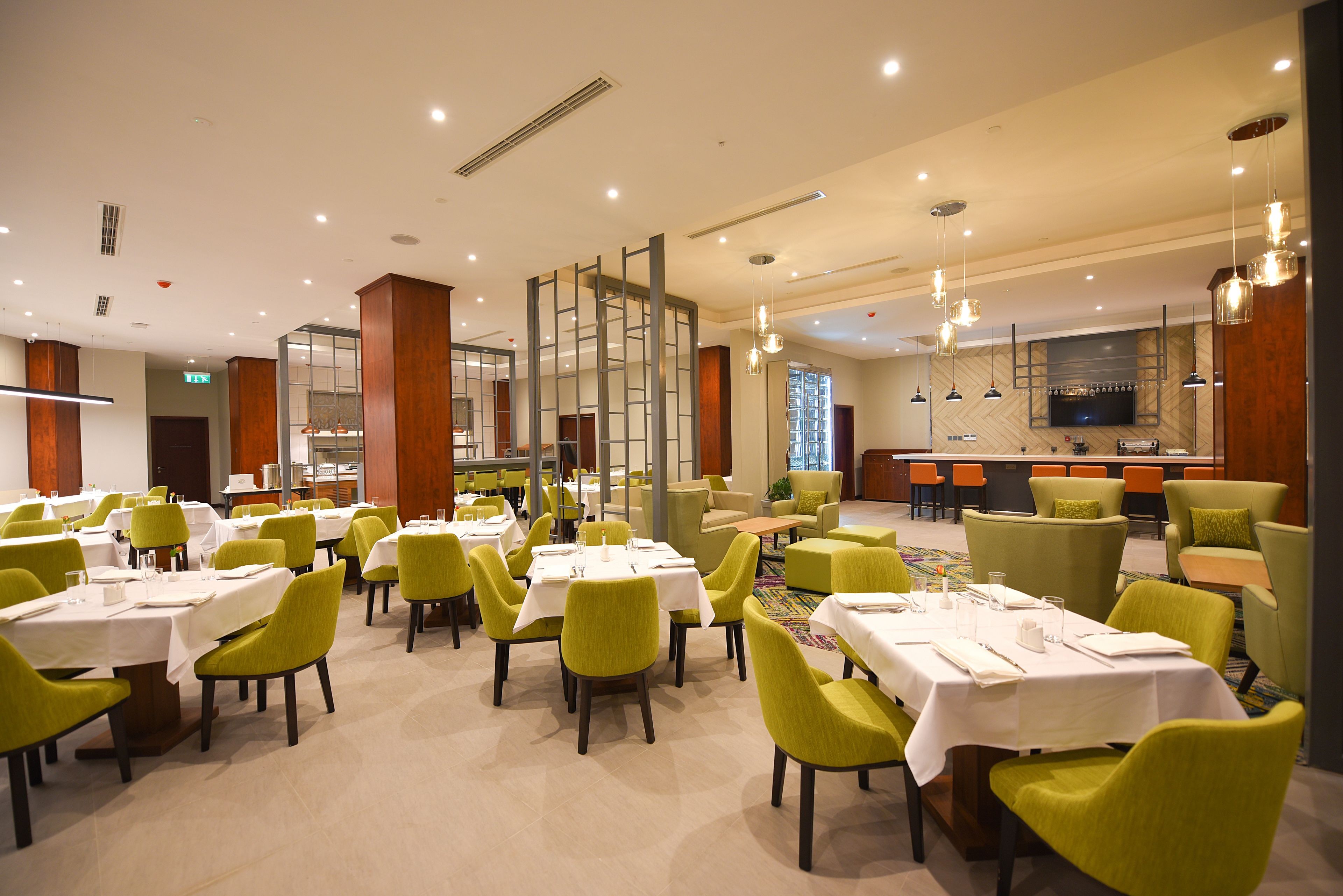 A dining area with tables and chairs, a bar area, and a television screen.