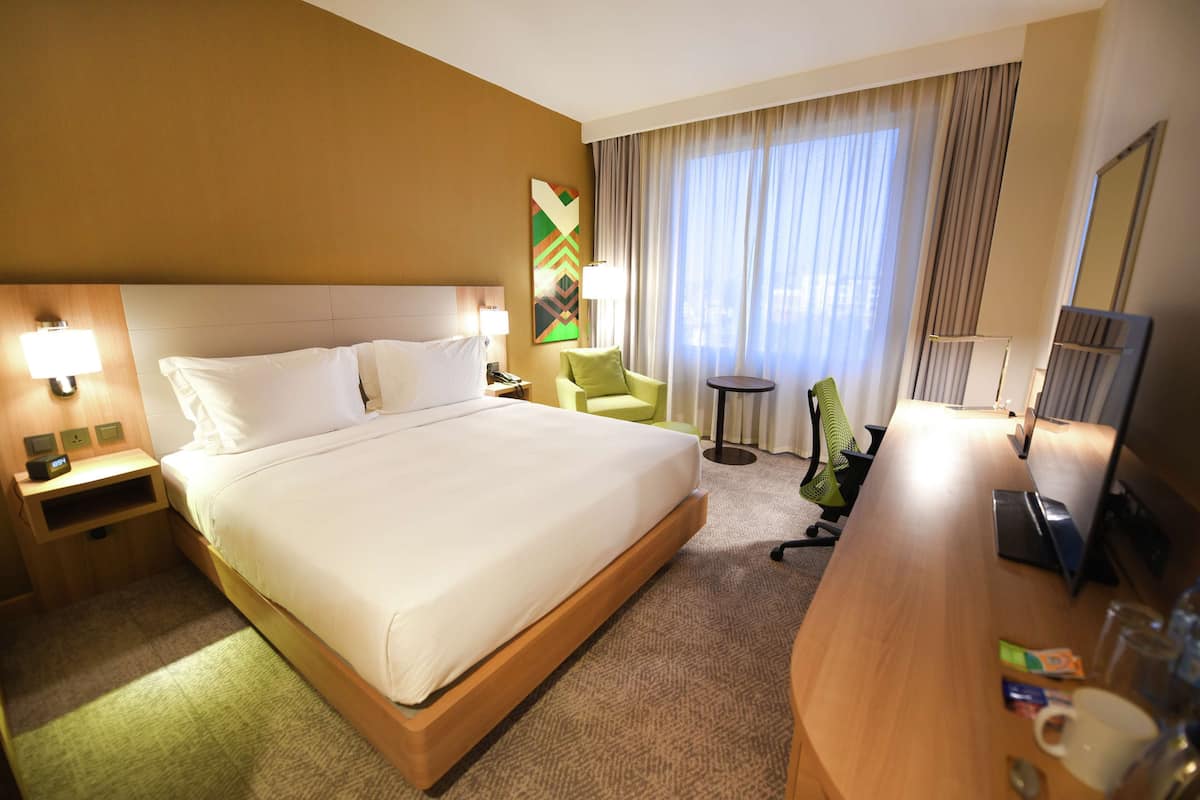 Une chambre d’hôtel avec un grand lit, un bureau, une chaise, une lampe et un téléviseur.