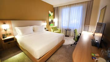 Ein Hotelzimmer mit einem großen Bett, einem Schreibtisch, einem Stuhl, einer Lampe und einem Fernseher.
