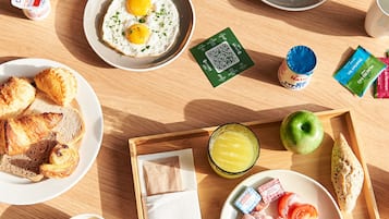 A breakfast tray with various food items including eggs, toast, ham, cheese, and a glass of juice.