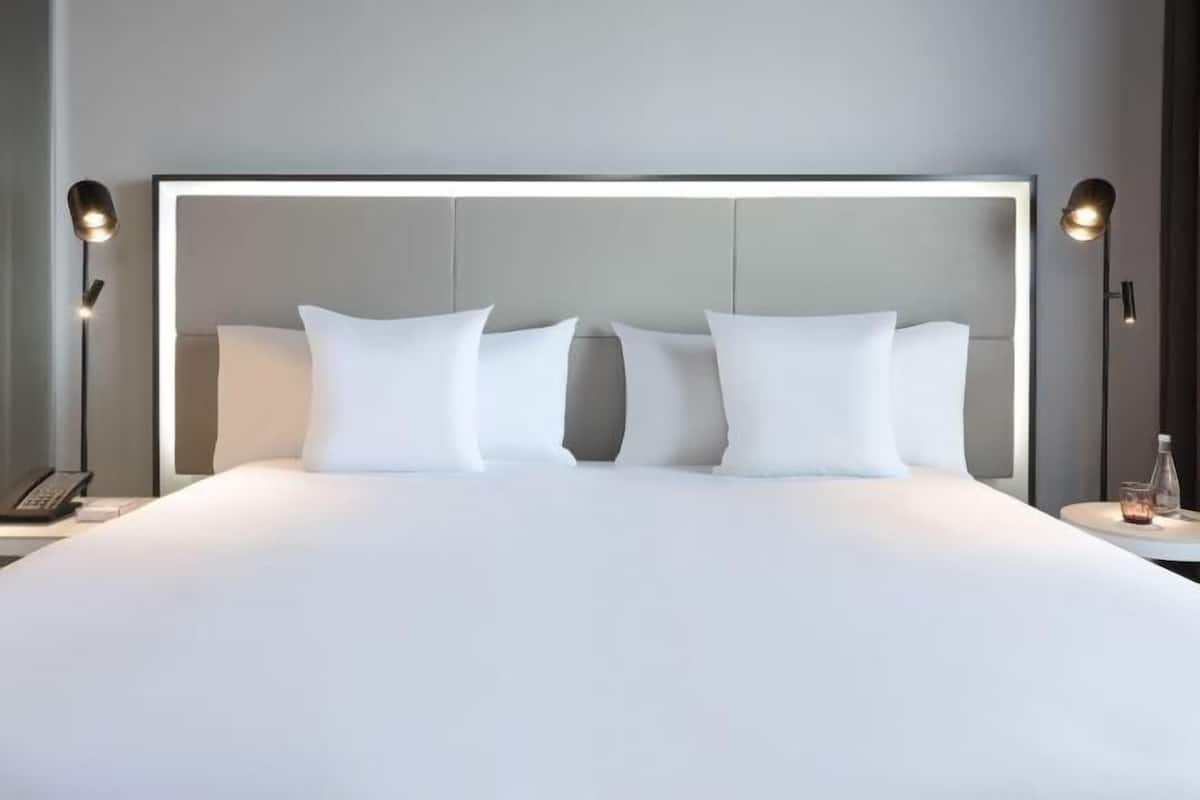 Un lit bien fait, avec du linge de lit blanc et une tête de lit moderne.