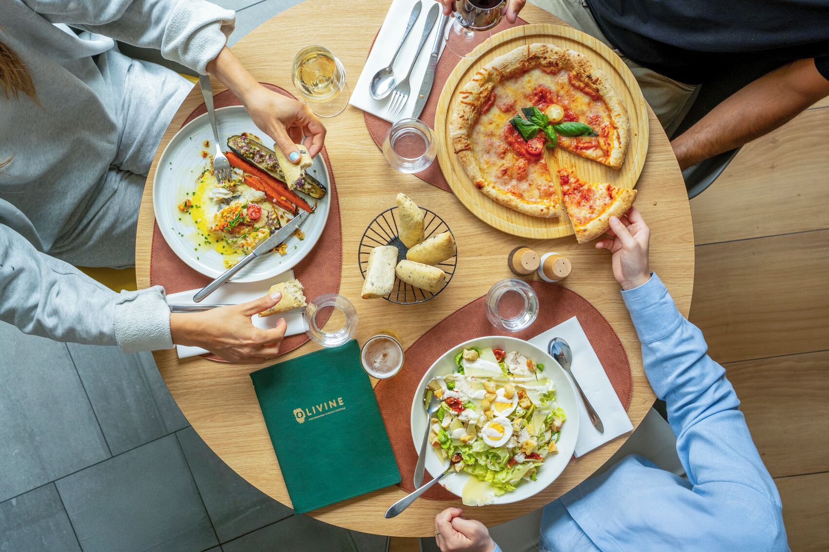 A round table with plates of food, a menu, and glasses of water and wine.