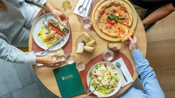 A round table with plates of food, a menu, and glasses of water and wine.