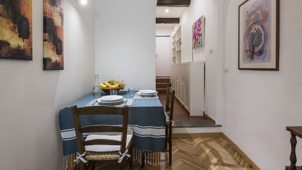 Comedor con una mesa dispuesta para dos personas, flanqueada por sillas de madera con manteles a rayas.