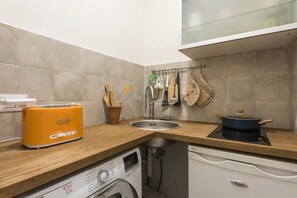 Une petite cuisine équipée d’un grille-pain, d’un évier et d’un égouttoir à vaisselle avec des ustensiles.