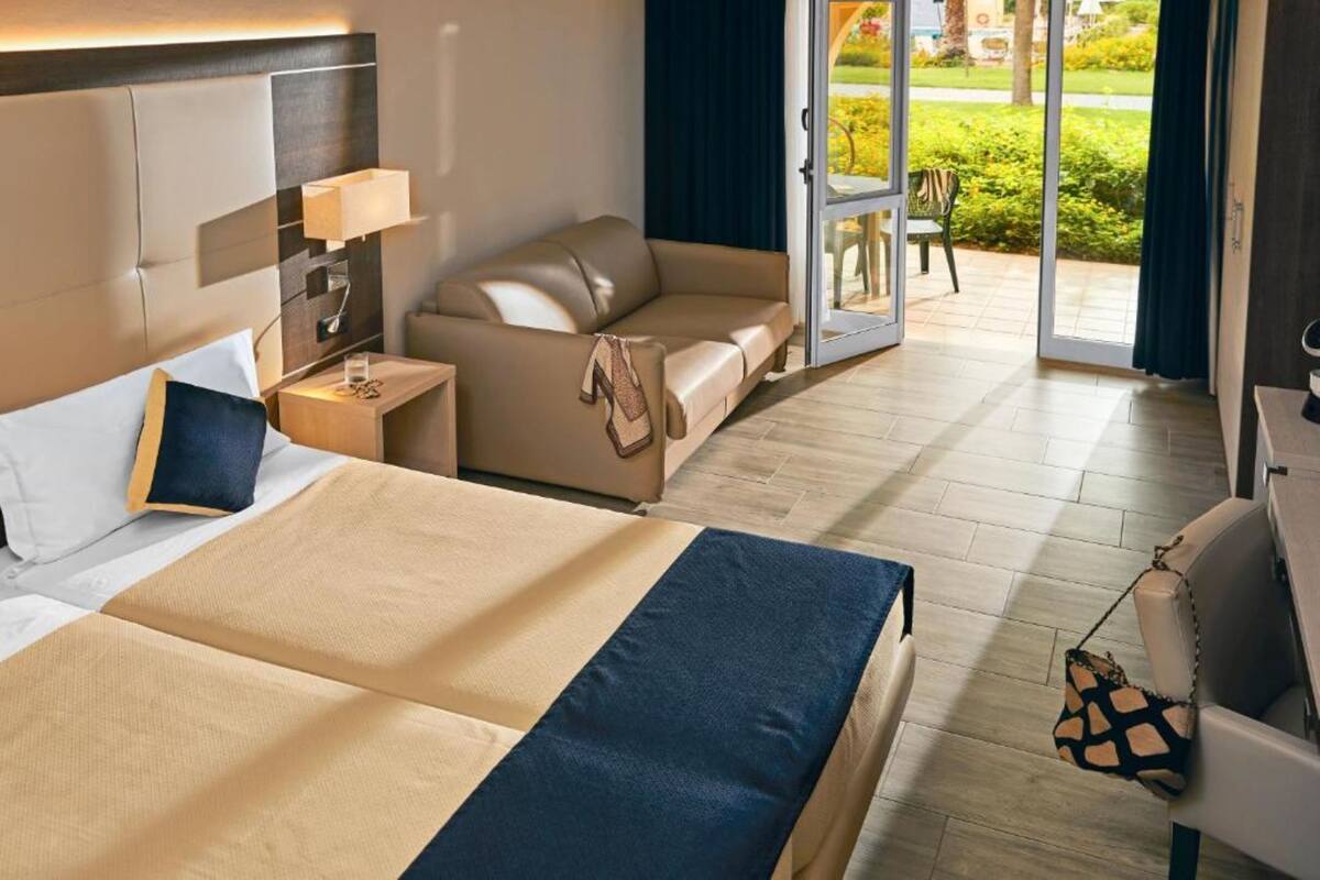 A hotel room with two beds, a sofa, a desk, and a chair.