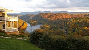 A house with a balcony overlooking a river and forested hills. - Inn at Riverbend (Pearisburg)