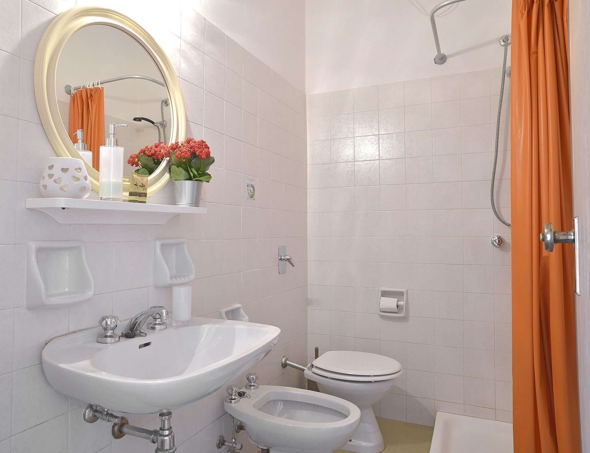A bathroom with a sink, toilet, and shower. There are toiletries on the sink and a mirror above it.