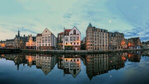 Paisagem urbana à beira-mar, com edifícios históricos refletidos em águas calmas.