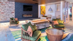 Een moderne woonkamer met een stenen muur, een flatscreen televisie, een open haard en moderne meubels.