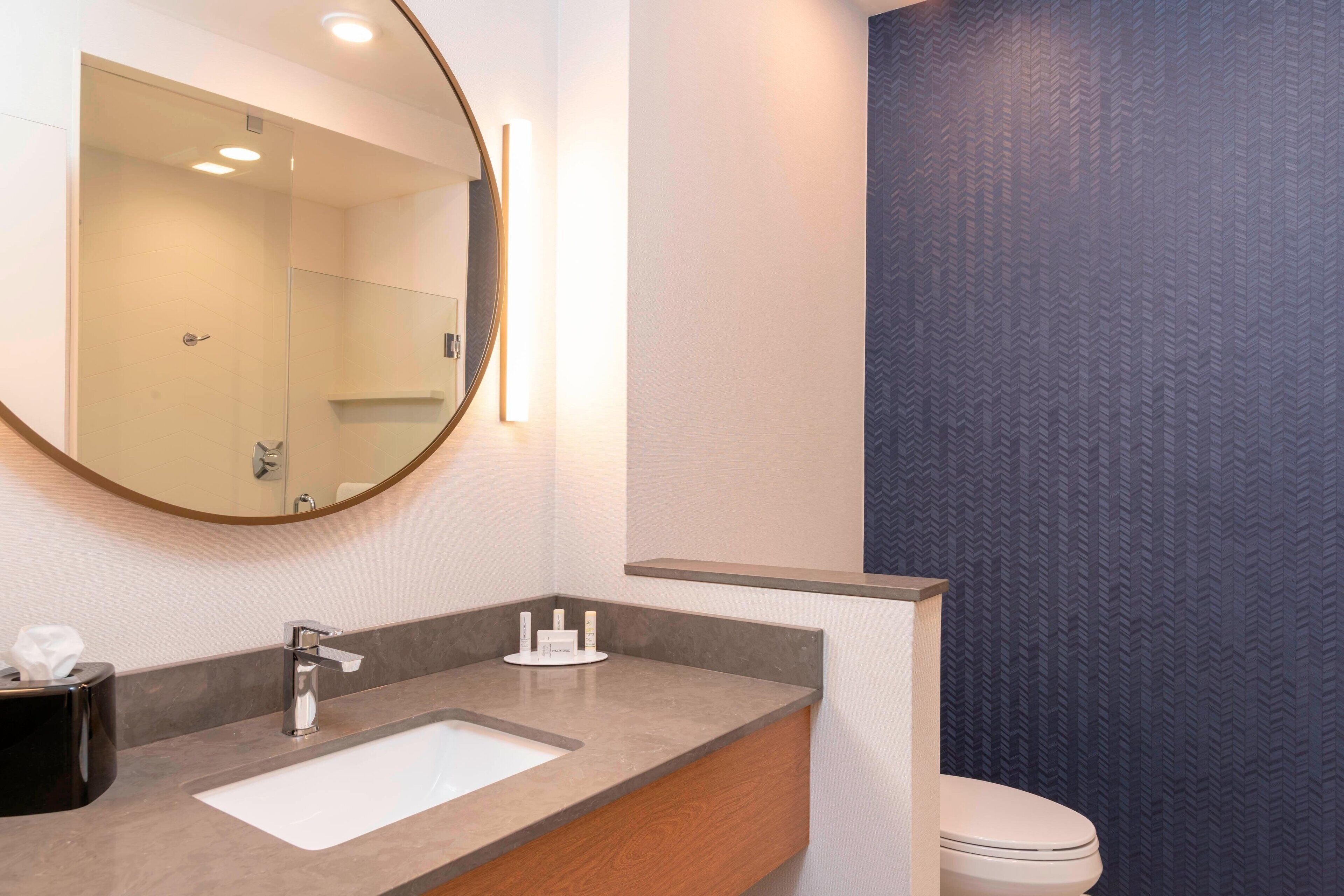 Un baño moderno con un espejo grande, un lavabo y un inodoro.