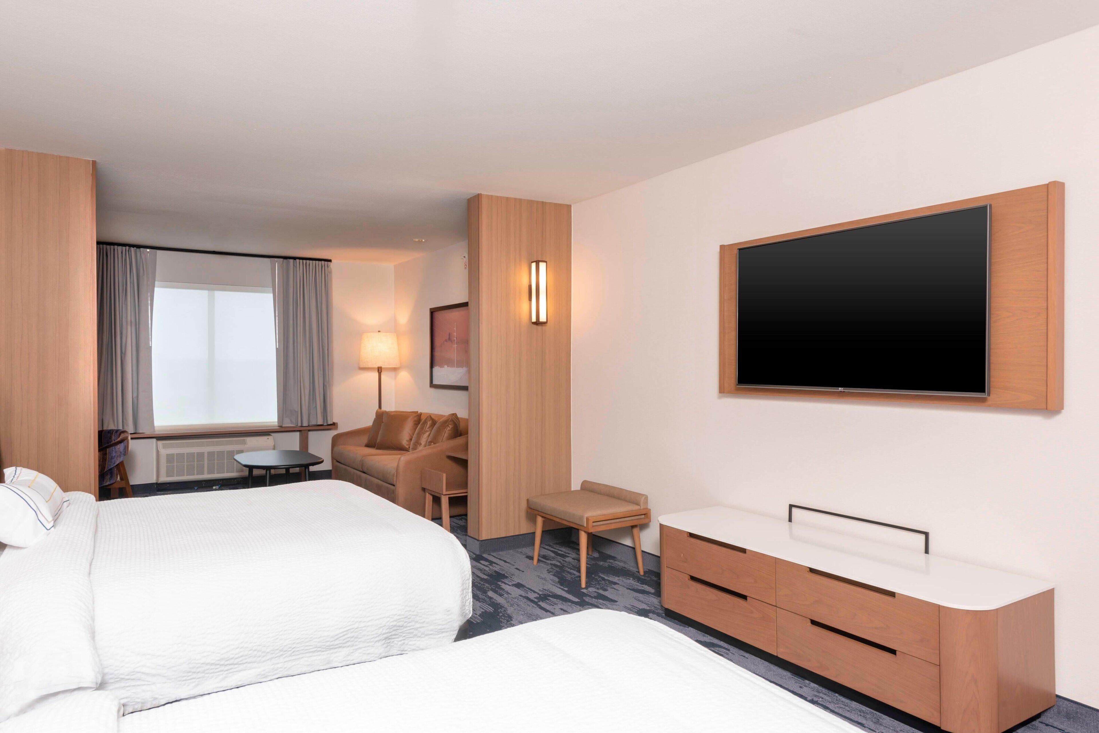 Hotellihuone, jossa on kaksi sänkyä, televisio, työpöytä ja tuoli.