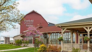 Een Fairfield Inn & Suites by Marriott gebouw met een rode gevel, grote ramen en een verzorgd gazon.