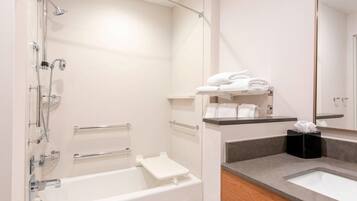A modern bathroom with a bathtub, a shower, a vanity with a sink, and a towel rack.