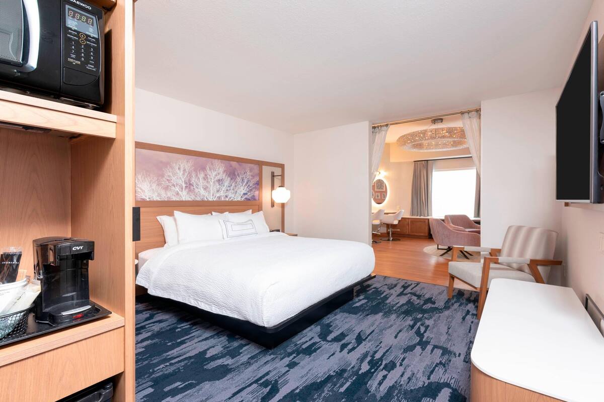 Une chambre d’hôtel équipée d’un lit, d’une machine à café, d’une télévision et d’un coin salon avec une chaise et une table.