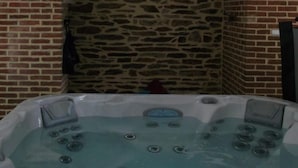 A hot tub with a stone wall and brick wall in the background. - La Sévinais (Retiers)
