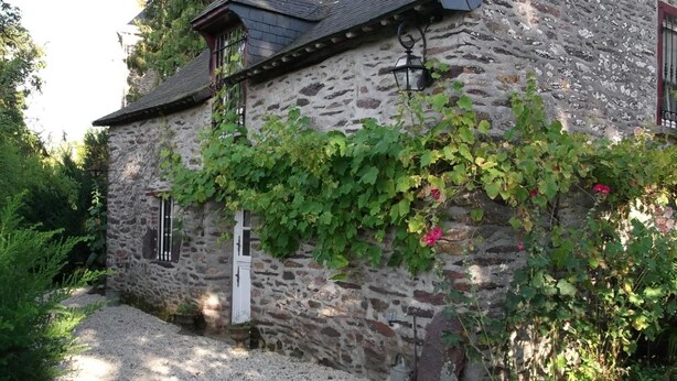 A stone building with a gravel path leading to a white door, surrounded by greenery and a stone wall. - La Sévinais (Retiers)