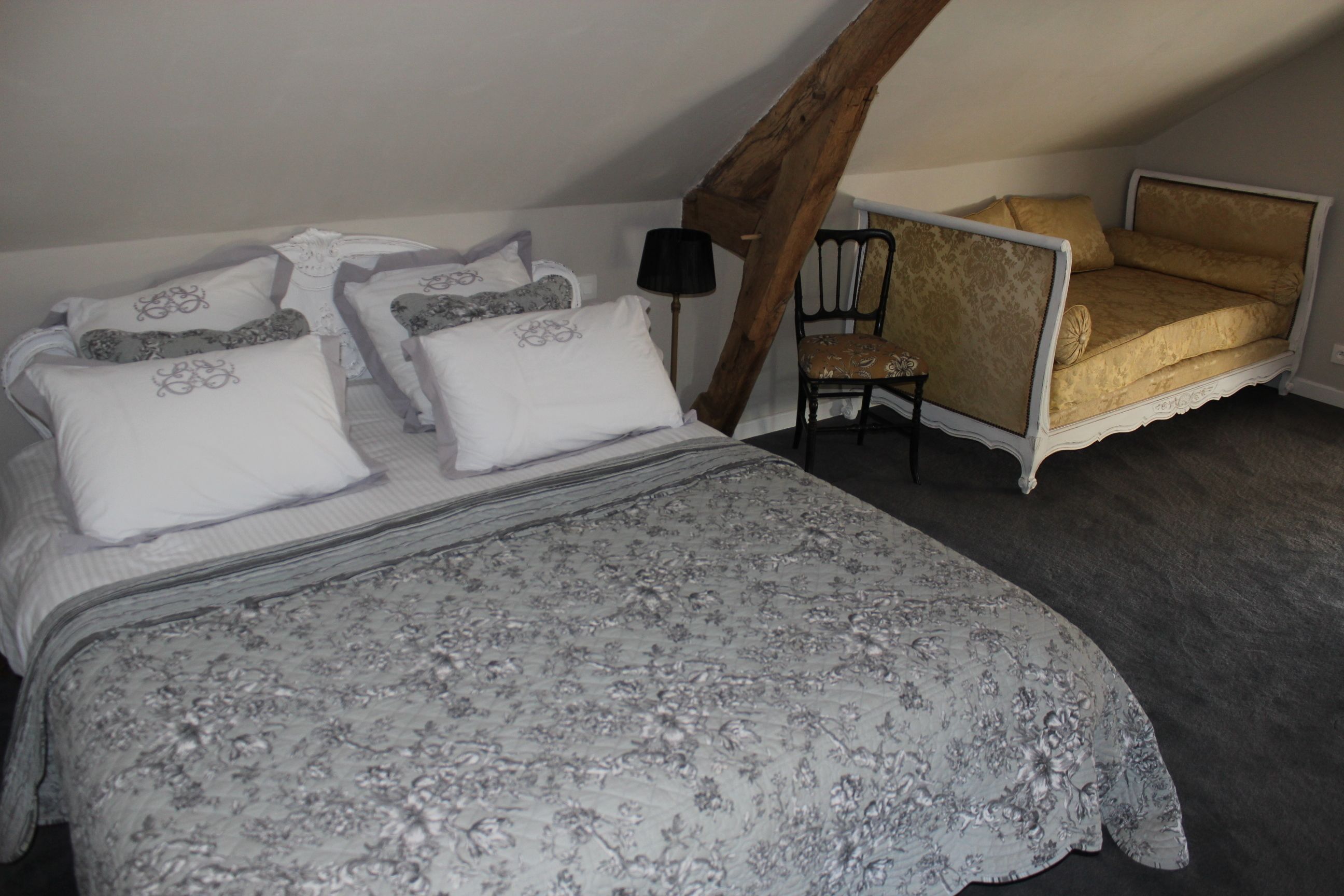 A bedroom with a large bed, a chair, and a small sofa.