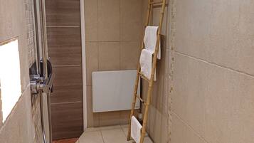 A small bathroom with a shower, a toilet, and a towel rack.