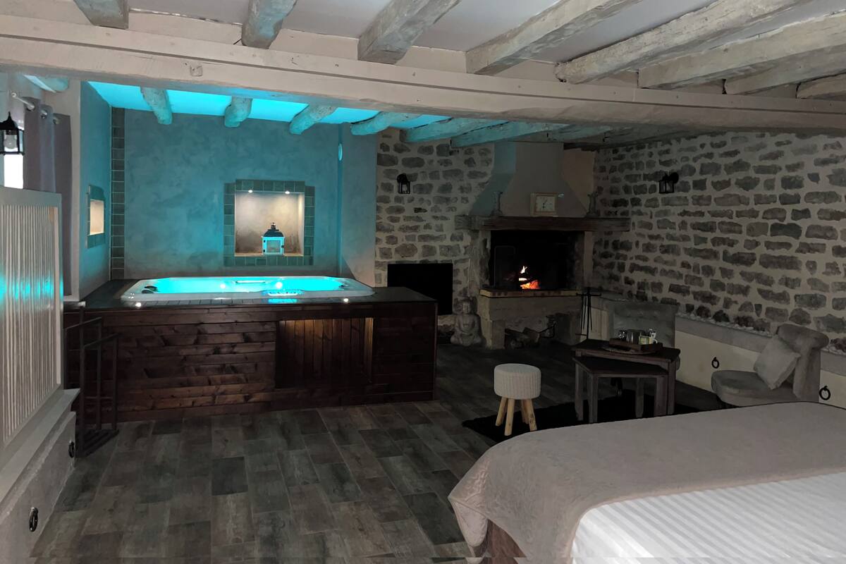Ein Zimmer mit Steinwand, Kamin, Whirlpool und einem Bett.