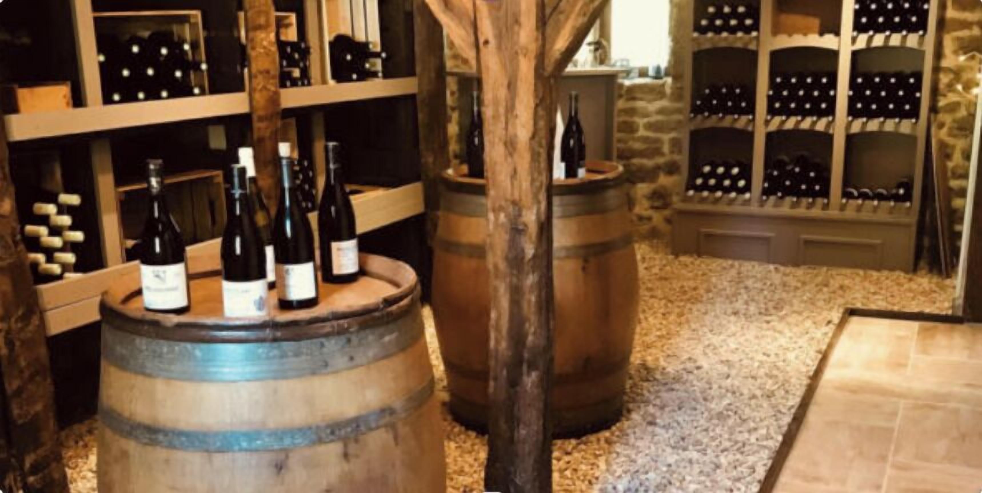 Una bodega con barriles de madera y estantes llenos de botellas de vino.