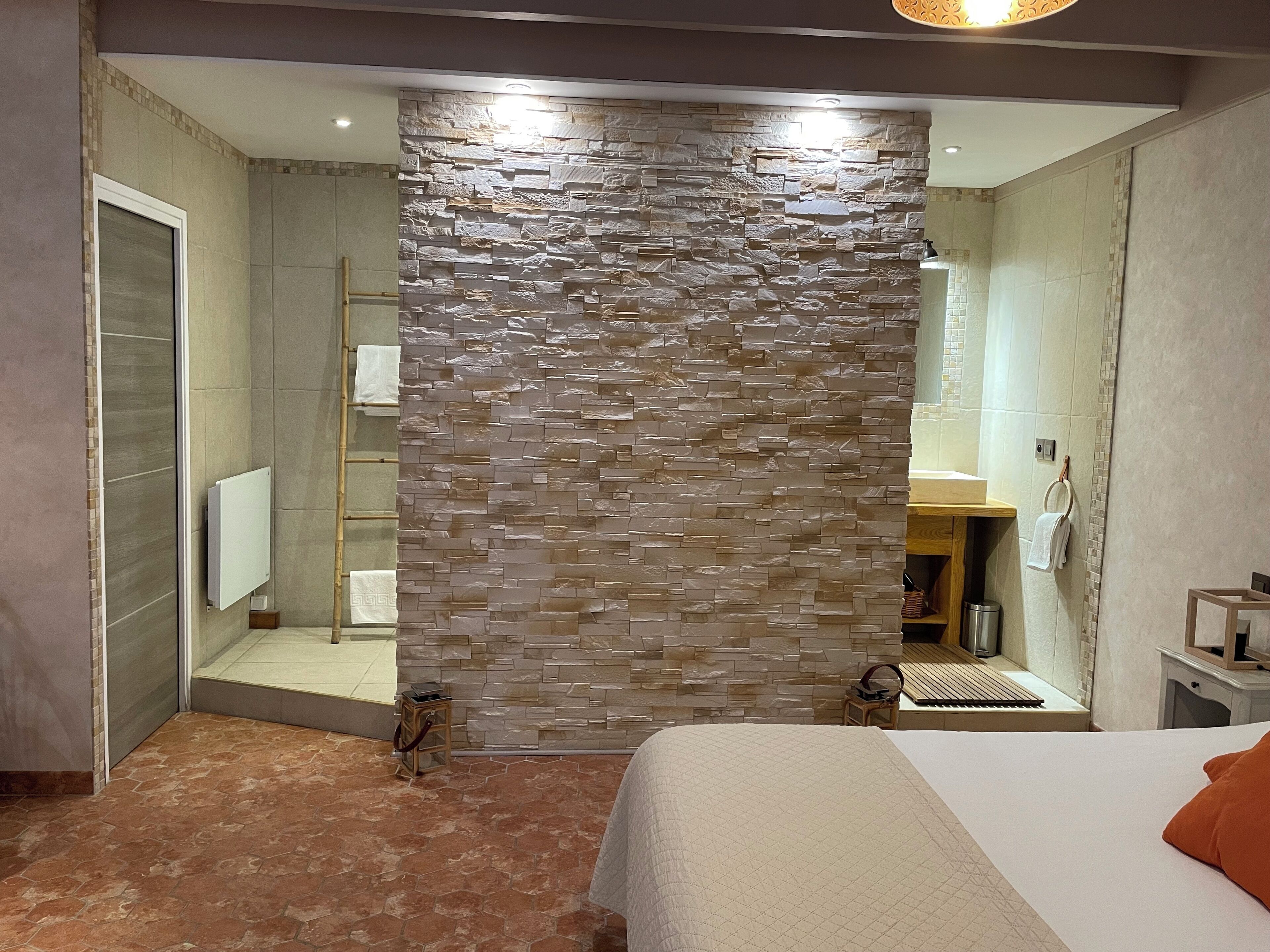 A modern bathroom with a stone wall, a shower, and a sink.