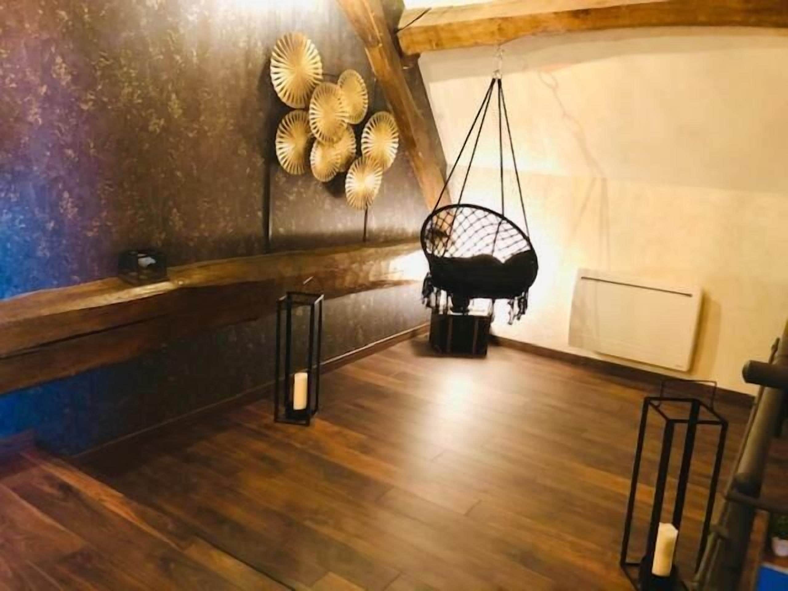 Une pièce de style loft avec un plafond en pente, des poutres en bois et un fauteuil suspendu.