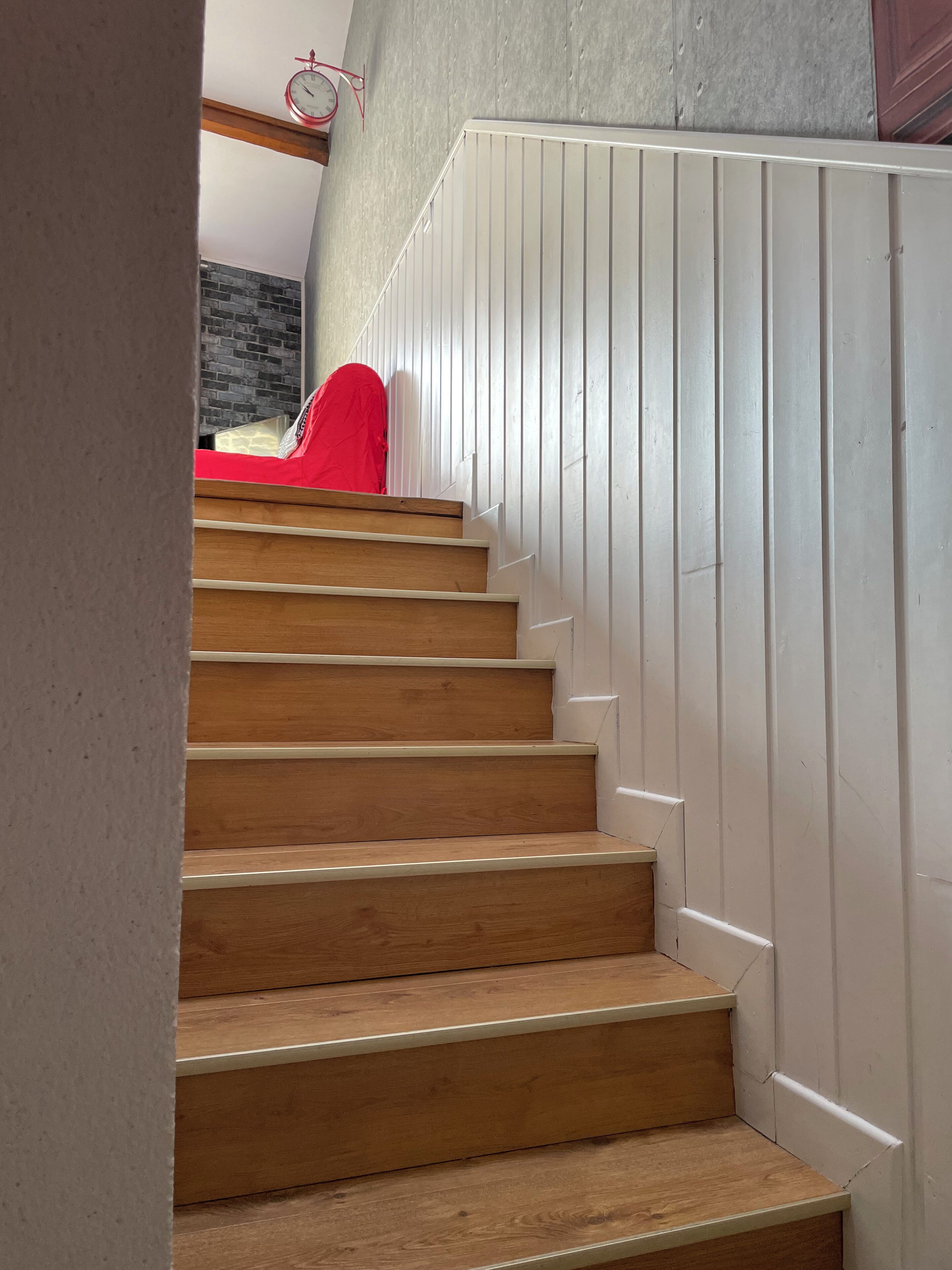 Una escalera de madera con paneles blancos en las paredes.