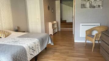 Ein Schlafzimmer mit Bett, Stuhl, Ablagefläche und einer Treppe, die in einen anderen Raum führt.