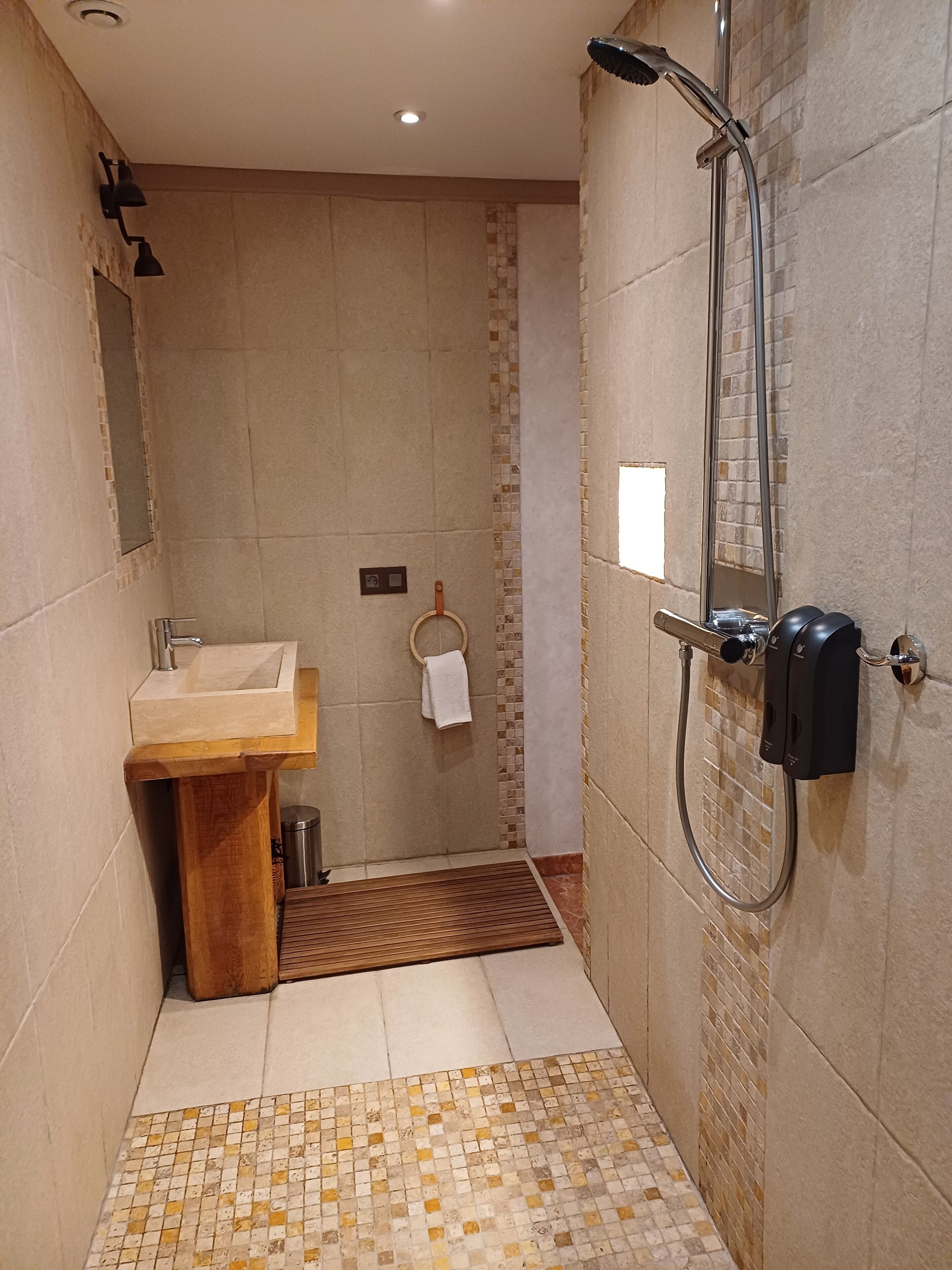 Un baño moderno con lavamanos, espejo y ducha.