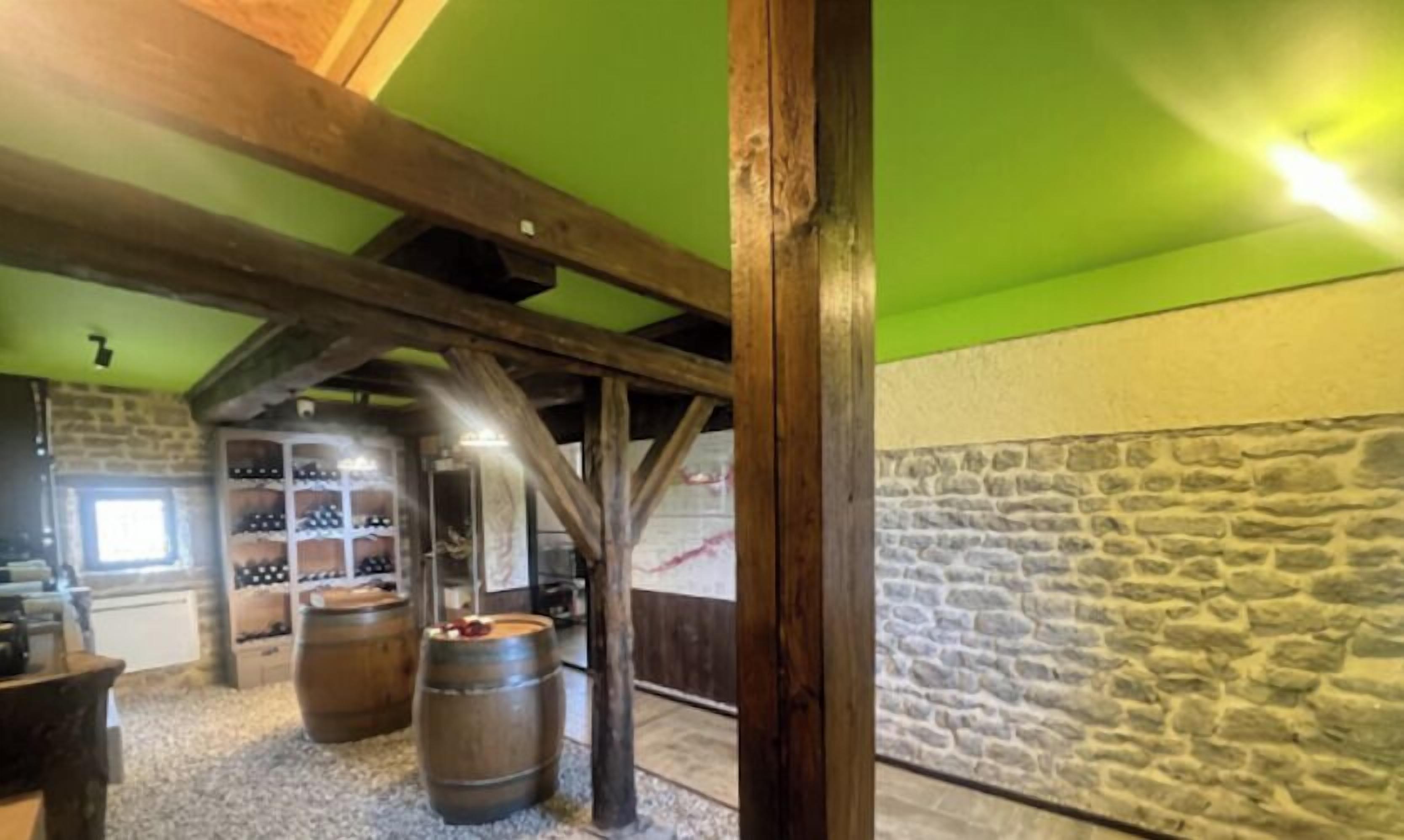 A rustic cellar with wooden beams, stone walls, and wine barrels.