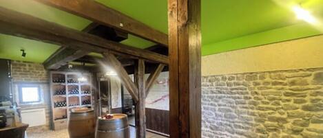 A rustic cellar with wooden beams, stone walls, and wine barrels.