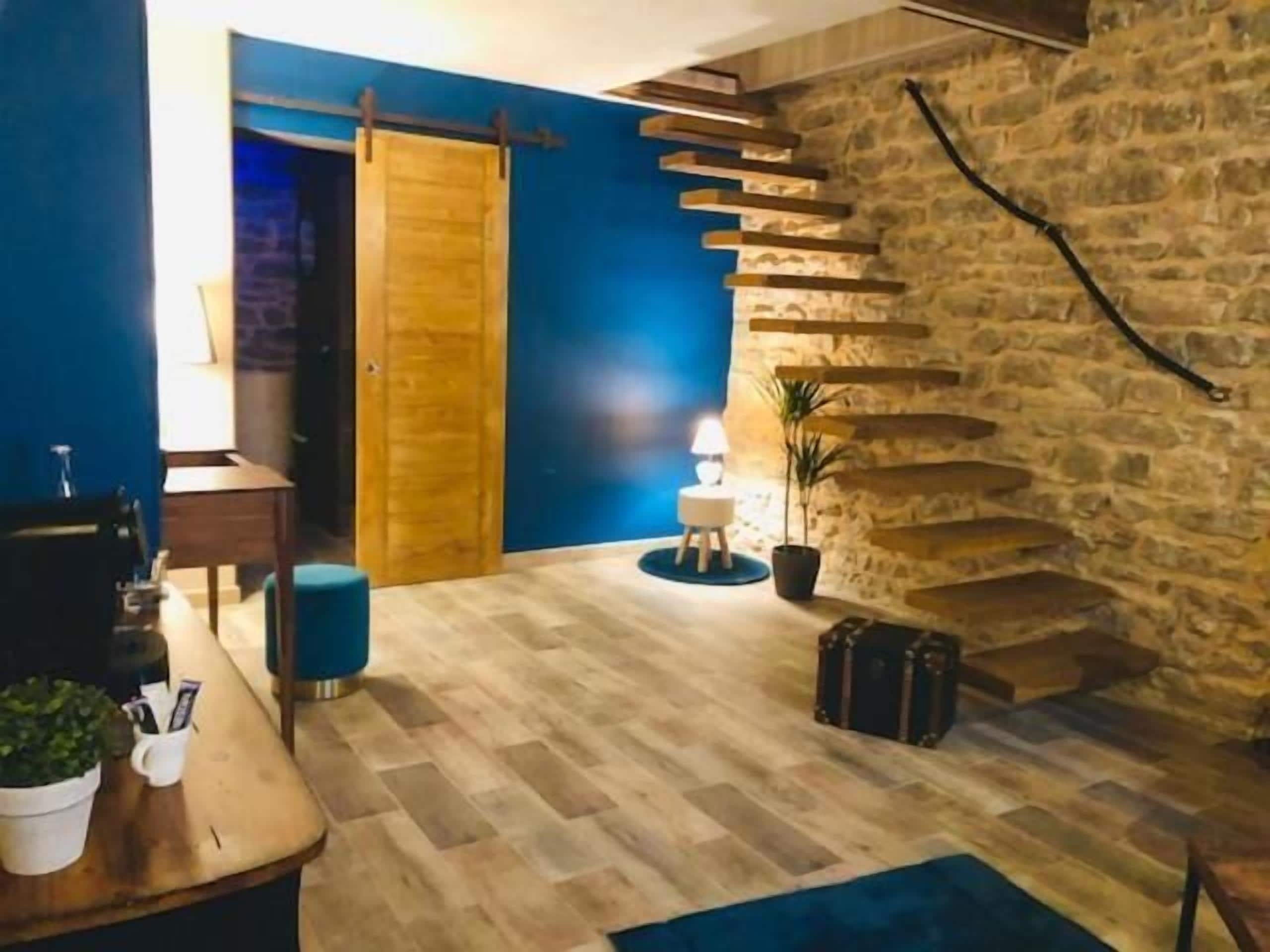 Un interior moderno con una escalera de madera, una pared azul y una pared de piedra.